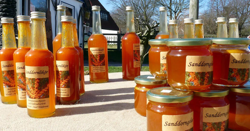 Bottles of sea buckthorn juice and liqueur and jars of sea buckthorn jelly on a table